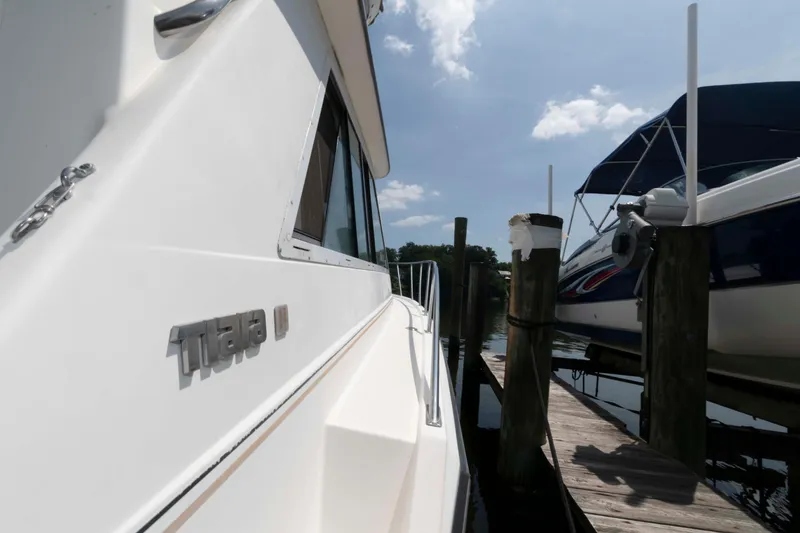 Slide: The Image of 1989 Tiara Yachts 36 Convertible docked beside another boat under a clear sky. - 5