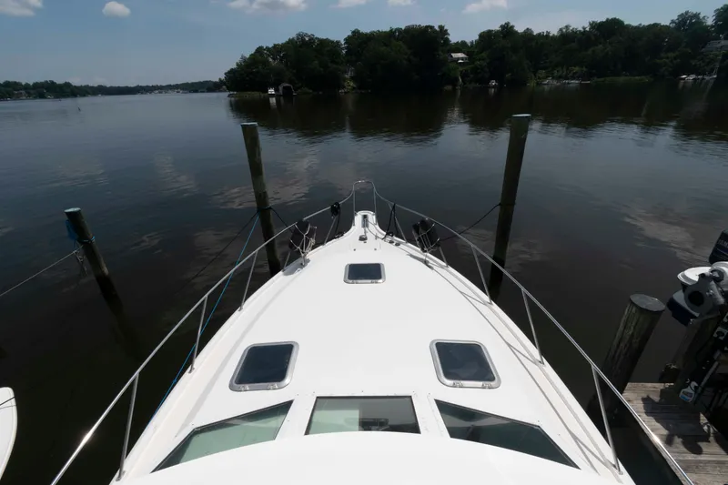 Slide: The Image of 1989 Tiara Yachts 36 Convertible docked on calm water, surrounded by trees. - 6