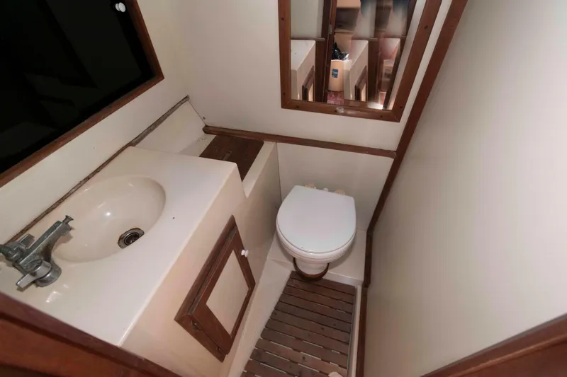 Slide: The Image of Compact bathroom in 1986 Shannon Brendan 32 boat, featuring sink, toilet, and wooden flooring. - 16