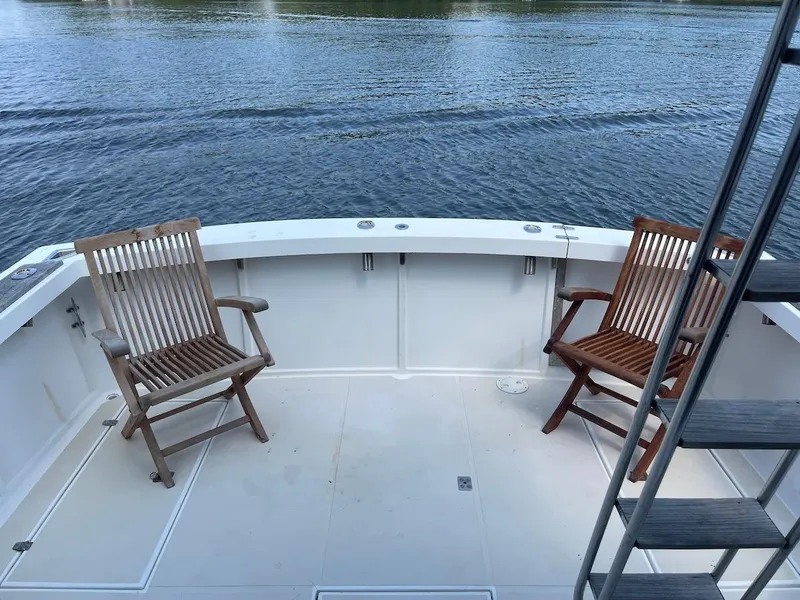 Slide: The Image of Two wooden chairs on a 1986 Shannon Brendan 32 boat deck by the water. - 2