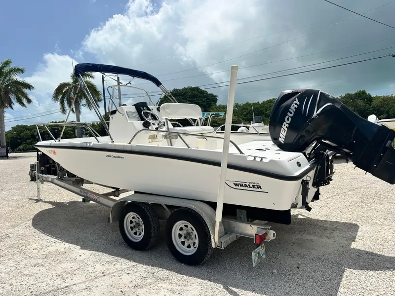 Slide: The Image of 2010 Boston Whaler 200 Dauntless boat on trailer with Mercury engine, parked outdoors. - 5
