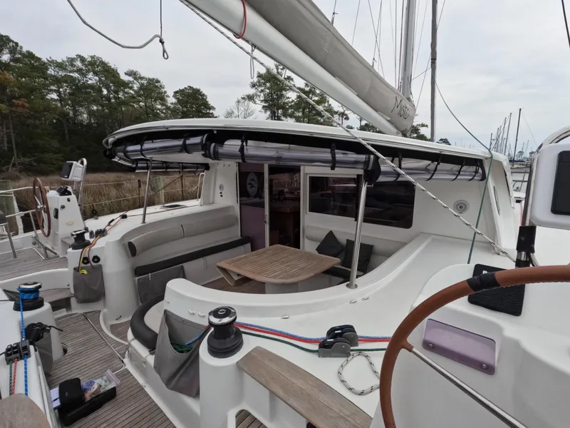 Slide: The Image of 2013 Nautitech 442 catamaran with spacious cockpit and seating area, docked near trees. - 3