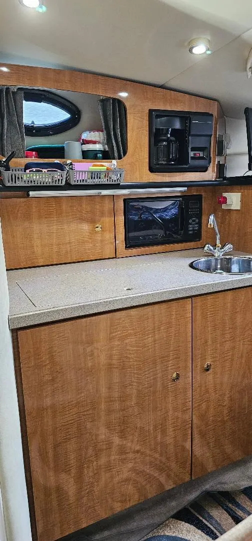 Slide: The Image of 2002 Regal Commodore 3060 boat kitchen with wood cabinets, microwave, and sink. - 6