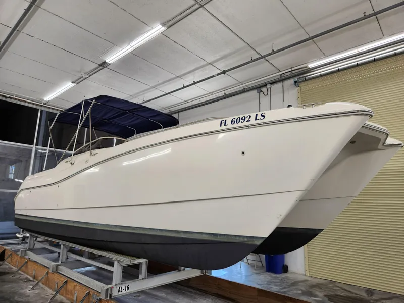 The Image of 2000 World Cat 266 Leisure Cat boat in indoor storage, featuring a blue canopy. - 0