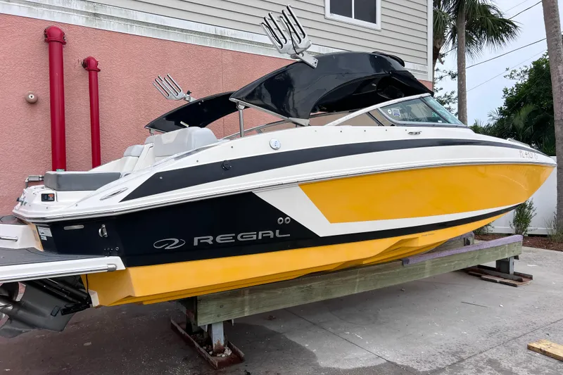 Slide: The Image of 2013 Regal 24 FasDeck RX boat with vibrant yellow and black design, docked outdoors. - 45