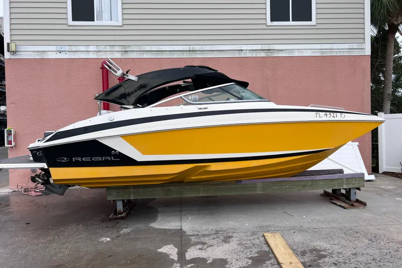 Slide: The Image of 2013 Regal 24 FasDeck RX boat in vibrant yellow, docked near a pink building. - 47