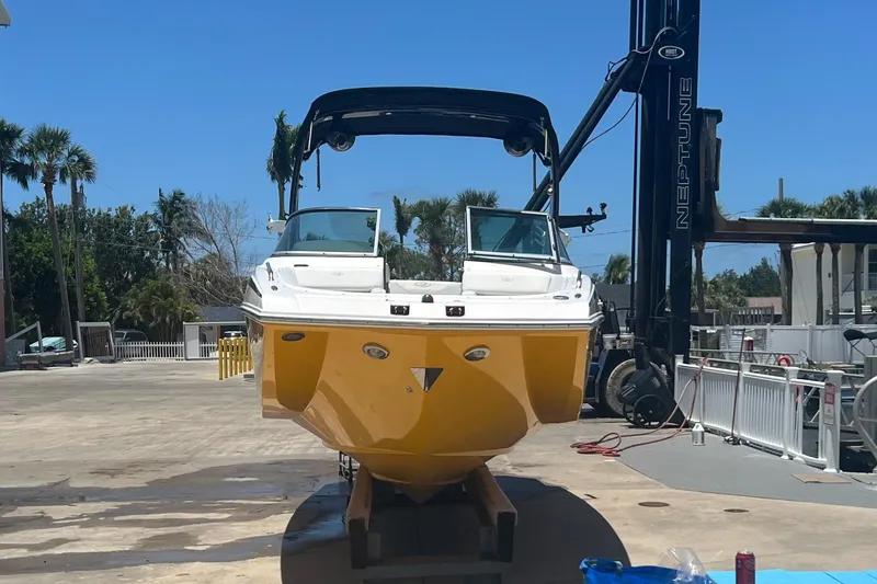 Slide: The Image of 2013 Regal 24 FasDeck RX boat with yellow hull on lift, surrounded by palm trees. - 5