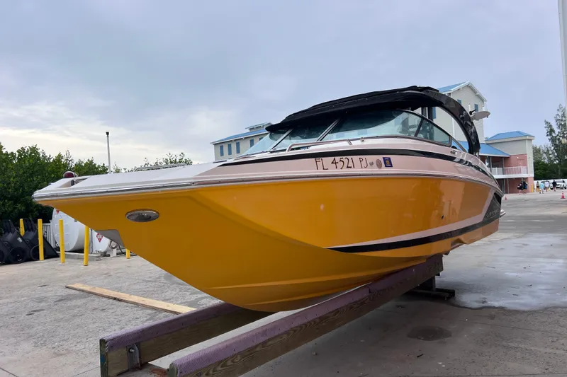 Slide: The Image of 2013 Regal 24 FasDeck RX boat with yellow hull on a trailer, parked outdoors. - 50