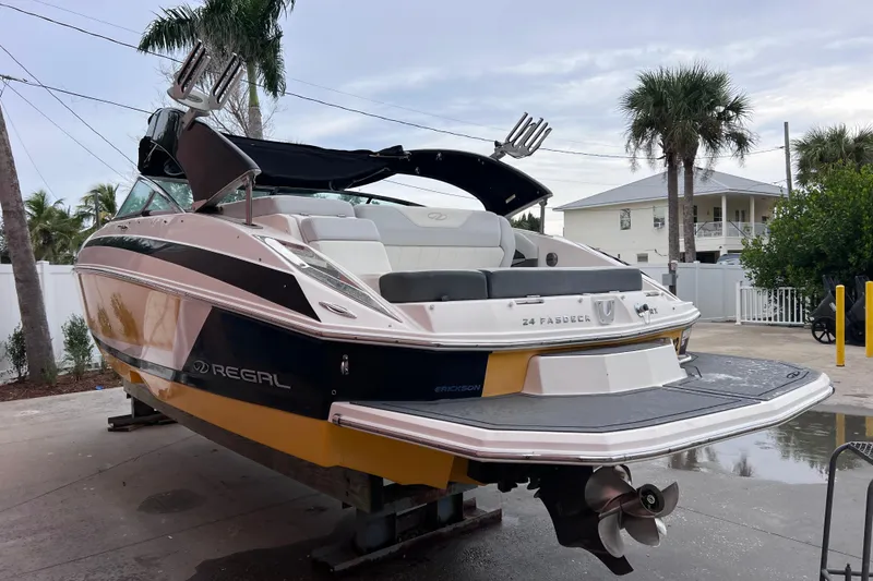 Slide: The Image of 2013 Regal 24 FasDeck RX boat on trailer, parked near palm trees and a house. - 51