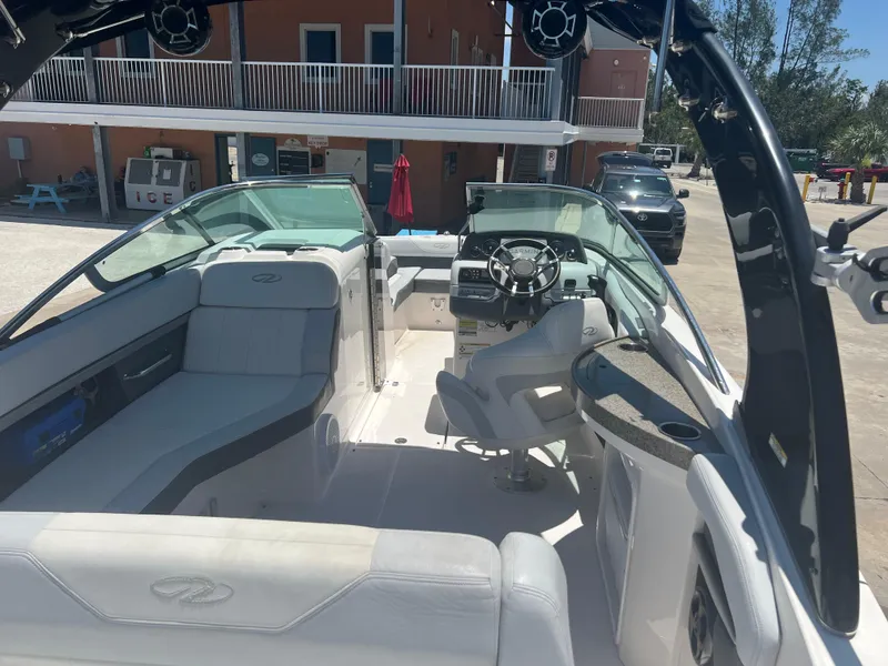 Slide: The Image of 2013 Regal 24 FasDeck RX boat interior with seating and steering wheel, docked outdoors. - 7