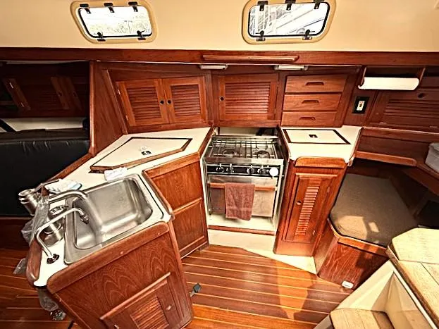 Slide: The Image of Interior of 1993 Tartan 3500 sailboat galley with wood cabinetry and stainless steel sink. - 23
