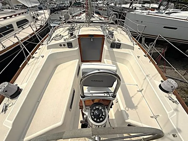 Slide: The Image of 1993 Tartan 3500 sailboat cockpit with steering wheel and navigation equipment, docked among other boats. - 5