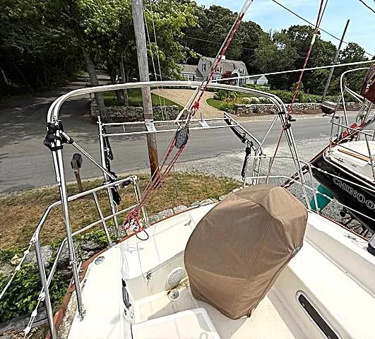 Slide: The Image of 1993 Tartan 3500 sailboat deck with covered equipment, docked near a road and trees. - 9