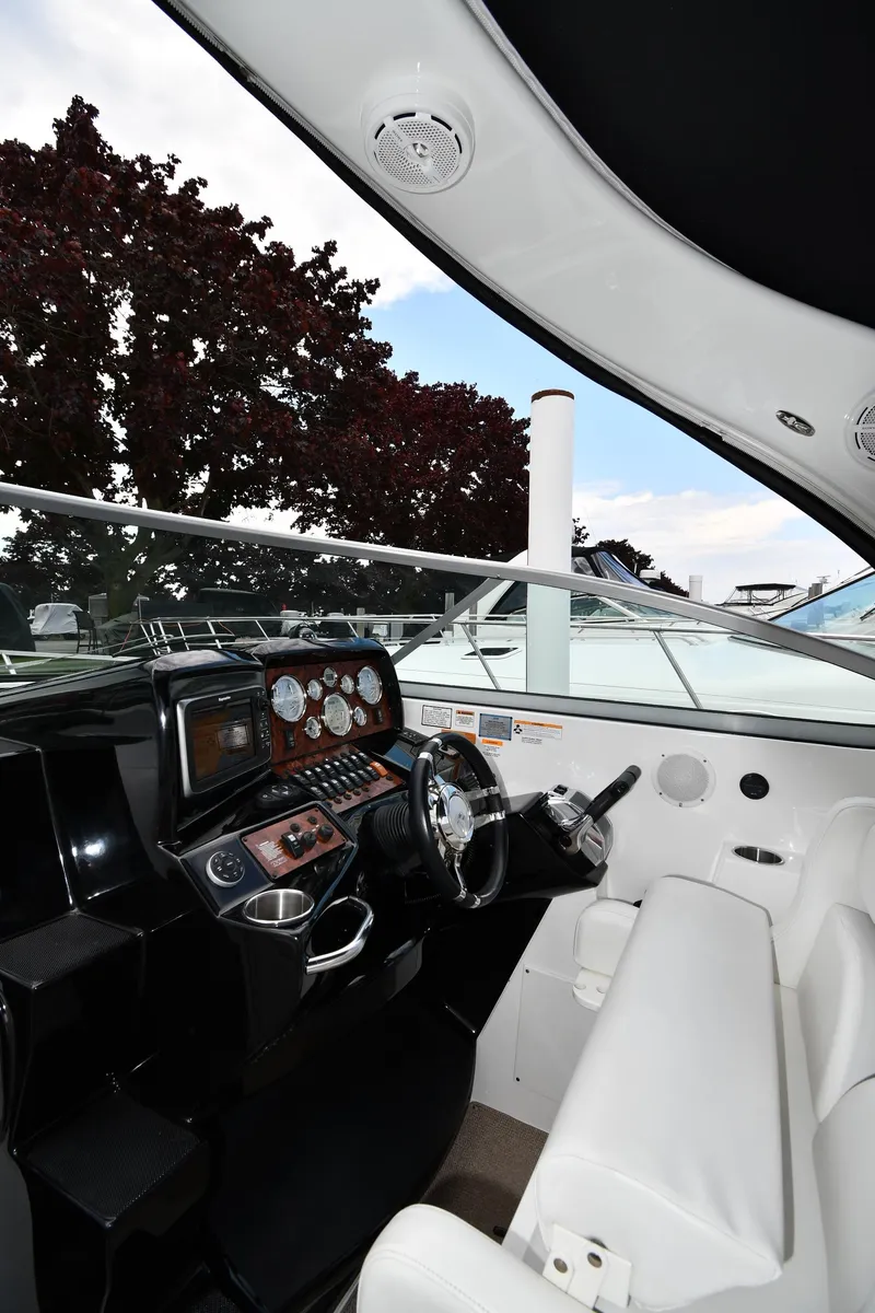 Slide: The Image of 2014 Rinker 310 Express Cruiser helm with modern controls and white seating. - 13