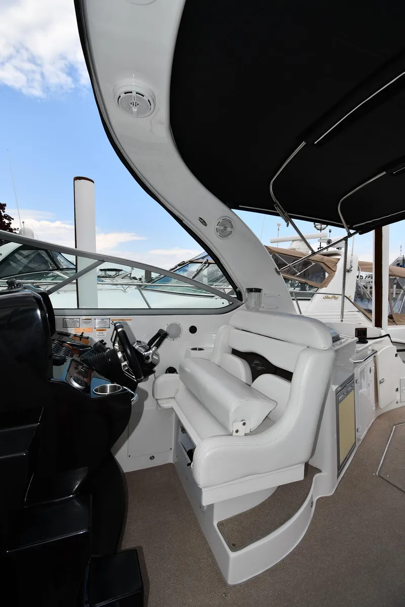 Slide: The Image of 2014 Rinker 310 Express Cruiser helm with white seating and black canopy. - 19