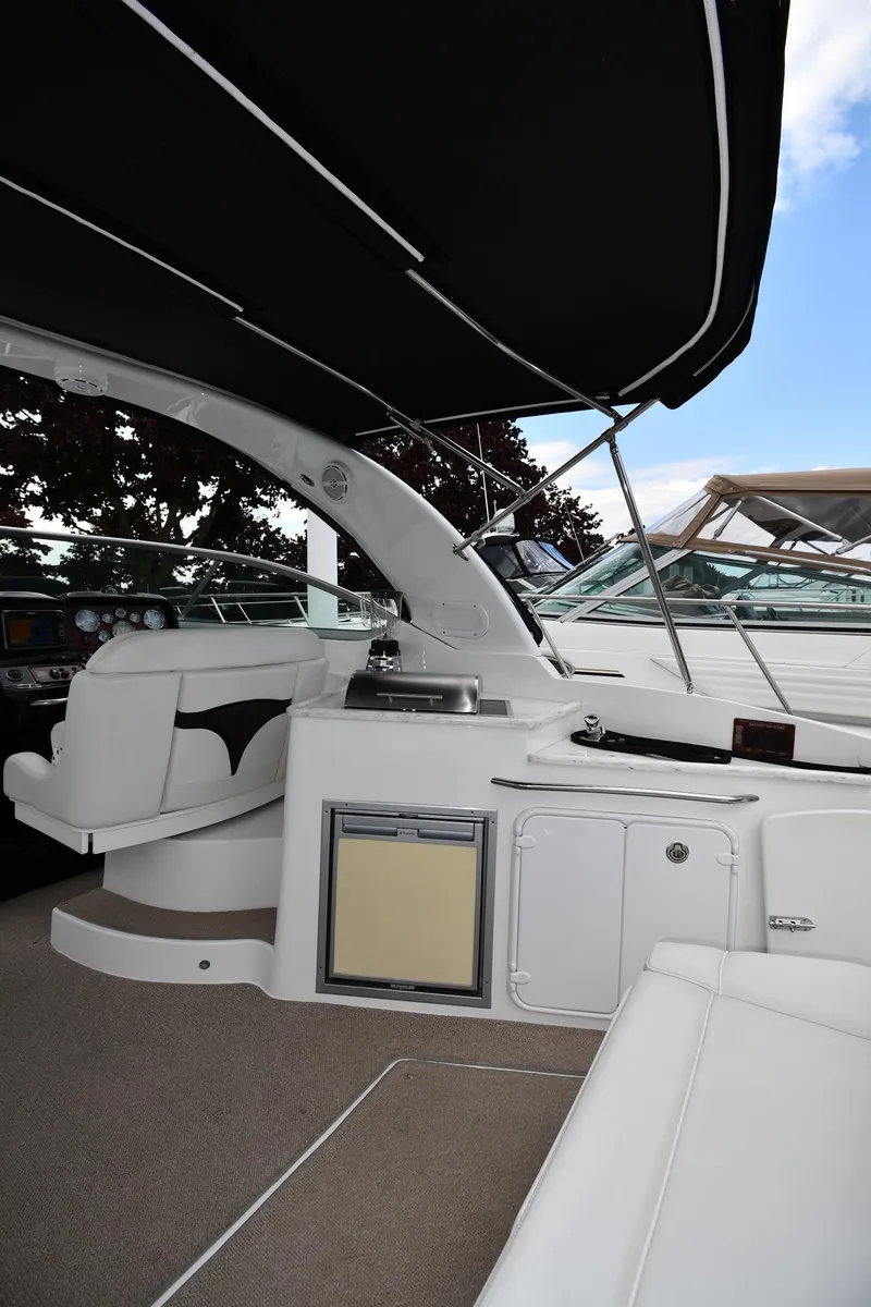 Slide: The Image of 2014 Rinker 310 Express Cruiser interior with seating and kitchenette under black canopy. - 21