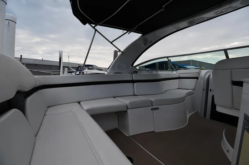 Slide: The Image of 2014 Rinker 310 Express Cruiser interior with white seating and canopy, docked at marina. - 22