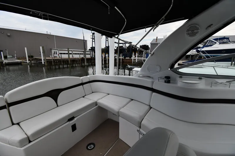 Slide: The Image of 2014 Rinker 310 Express Cruiser interior with white seating, docked at marina. - 24