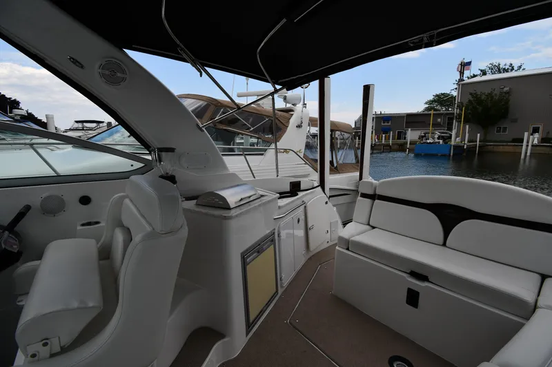 Slide: The Image of 2014 Rinker 310 Express Cruiser interior with seating and helm, docked at marina. - 25