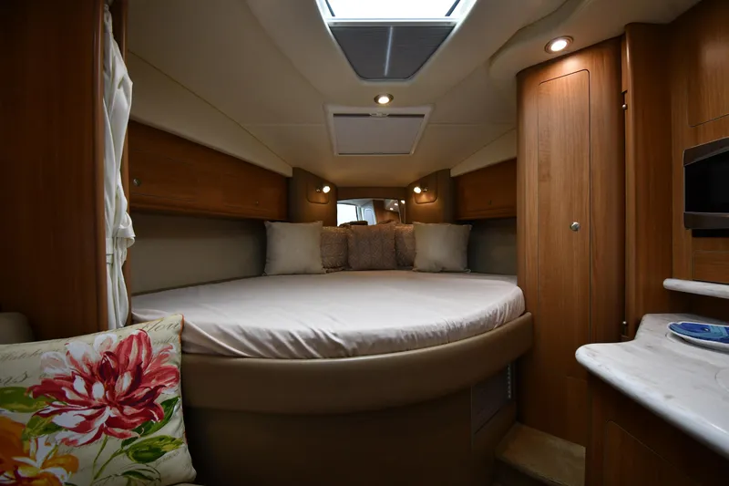 Slide: The Image of 2014 Rinker 310 Express Cruiser interior with cozy bed and wooden cabinetry. - 37