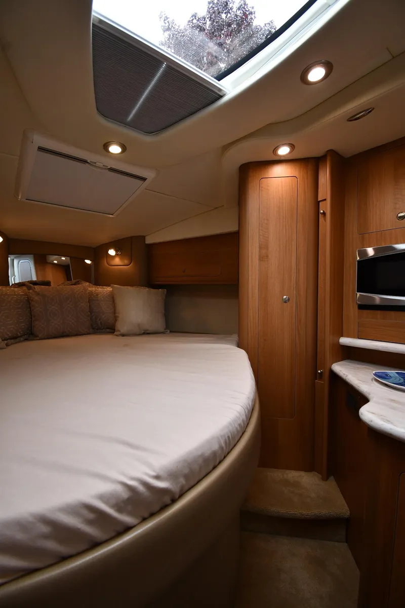 Slide: The Image of 2014 Rinker 310 Express Cruiser cabin interior with bed, skylight, and wooden cabinetry. - 38