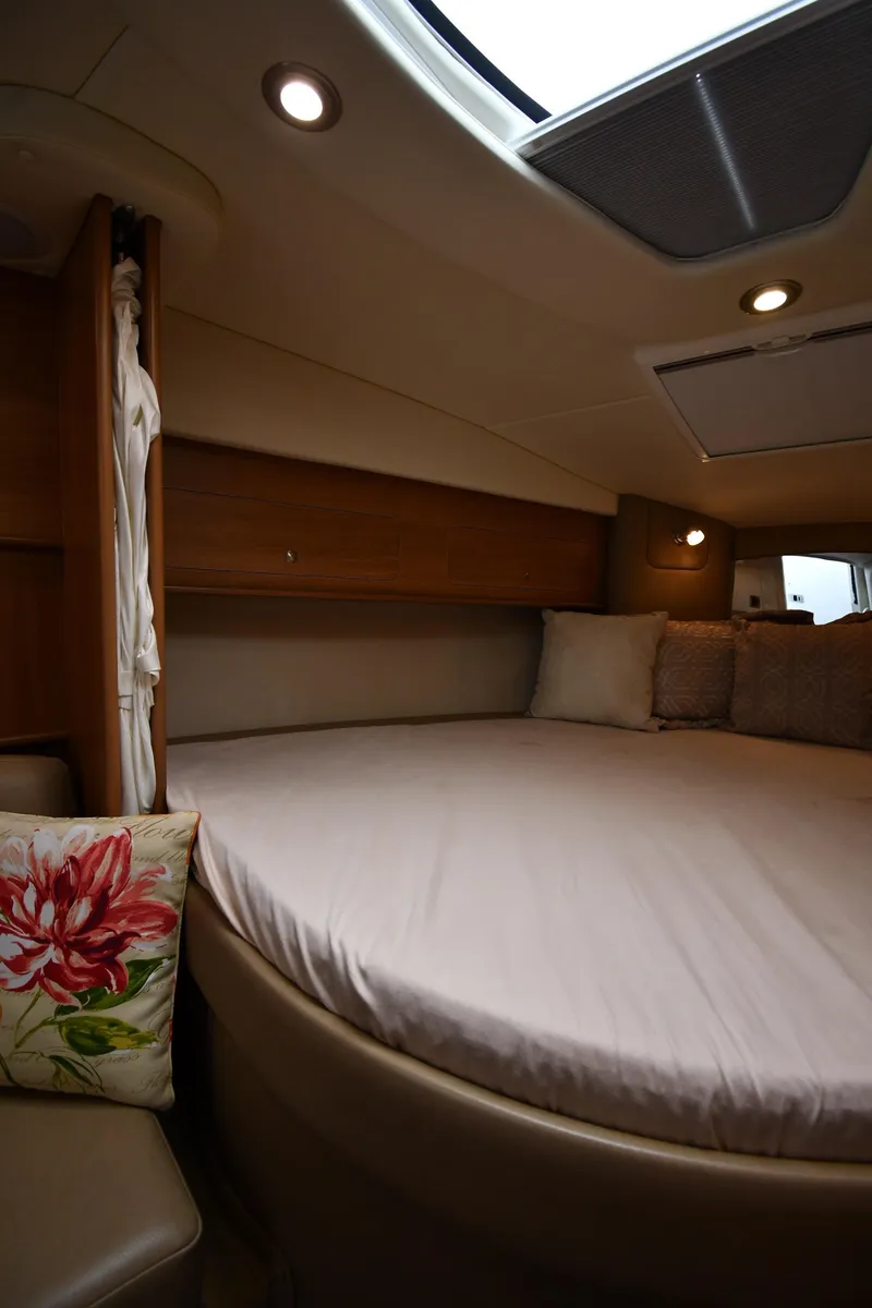 Slide: The Image of 2014 Rinker 310 Express Cruiser cabin with cozy bed and ambient lighting. - 39