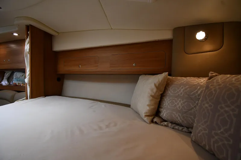 Slide: The Image of 2014 Rinker 310 Express Cruiser cabin with cozy bed and wooden storage cabinets. - 40