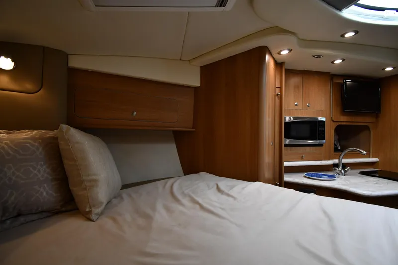 Slide: The Image of 2014 Rinker 310 Express Cruiser interior with bed, kitchenette, and modern amenities. - 41