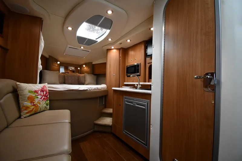 Slide: The Image of 2014 Rinker 310 Express Cruiser interior with cozy seating, kitchenette, and bed. - 42
