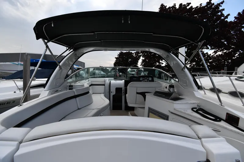 Slide: The Image of 2014 Rinker 310 Express Cruiser interior with seating and helm, docked under a canopy. - 9