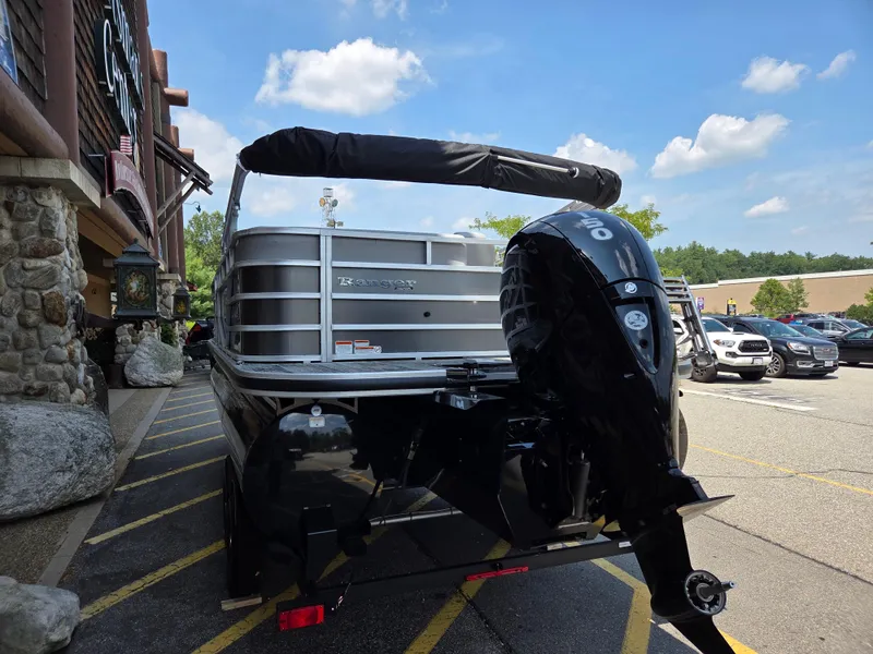 Slide: The Image of 2024 Ranger Reata 223C pontoon boat with outboard motor in a parking lot. - 2