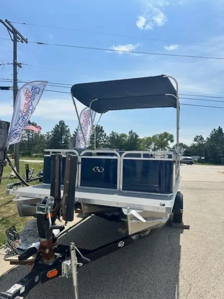 Slide: The Image of 2026 Paddle King Lo Pro Cruiser pontoon boat in showroom with canopy and motor. - 1