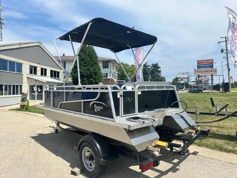 Slide: The Image of 2026 Paddle King Lo Pro Cruiser pontoon boat in showroom, featuring blue panels and seating. - 3