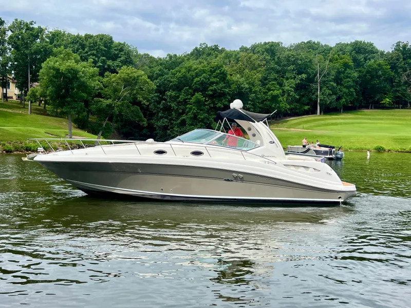 The Image of 2006 Sea Ray 340 Sundancer cruising on a scenic lake with lush green trees. - 0