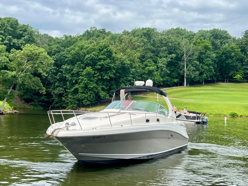 Slide: The Image of 2006 Sea Ray 340 Sundancer cruising on a serene lake with lush green forest backdrop. - 1