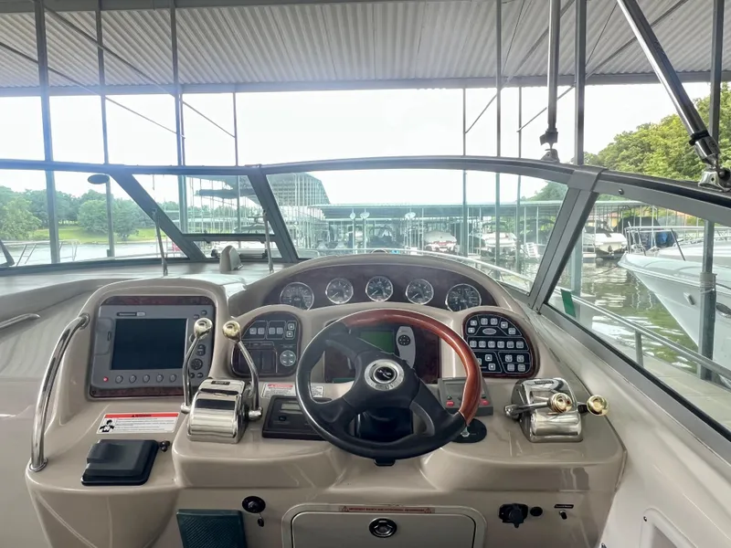 Slide: The Image of 2006 Sea Ray 340 Sundancer helm with modern controls and gauges, docked in a marina. - 10