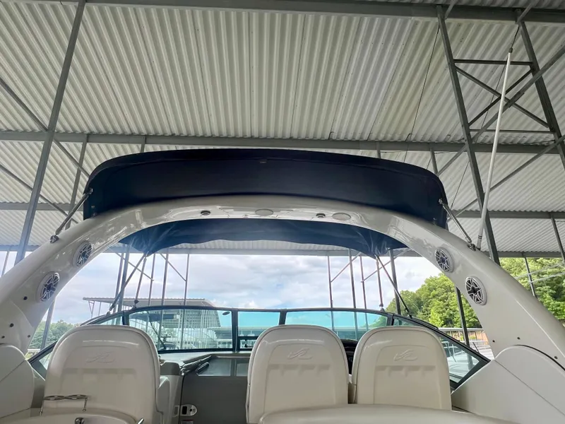 Slide: The Image of 2006 Sea Ray 340 Sundancer boat interior under a metal canopy, featuring white seating and speakers. - 13