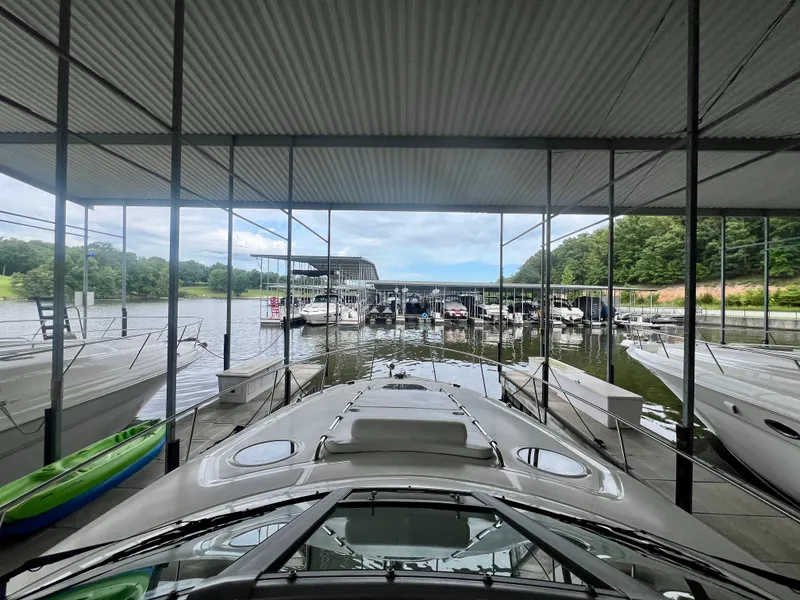 Slide: The Image of 2006 Sea Ray 340 Sundancer docked in a marina with surrounding boats and lush greenery. - 16