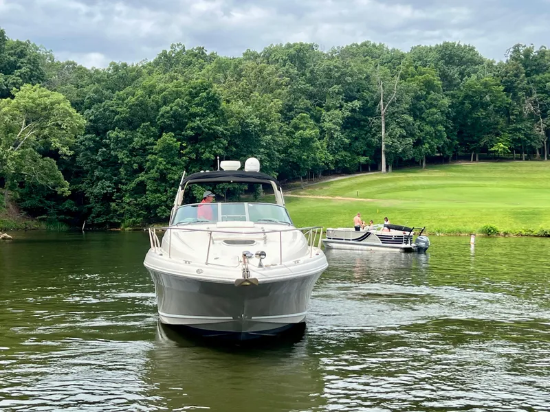 Slide: The Image of 2006 Sea Ray 340 Sundancer cruising on a serene lake with lush green forest backdrop. - 3