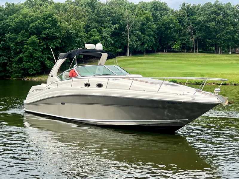 Slide: The Image of 2006 Sea Ray 340 Sundancer cruising on a serene lake with lush green trees. - 4