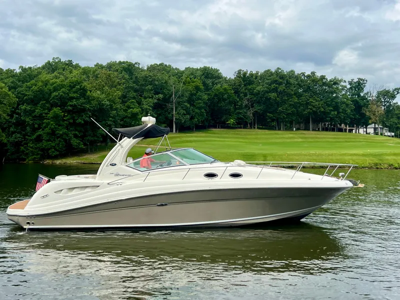 Slide: The Image of 2006 Sea Ray 340 Sundancer yacht cruising on a serene lake with lush green surroundings. - 5