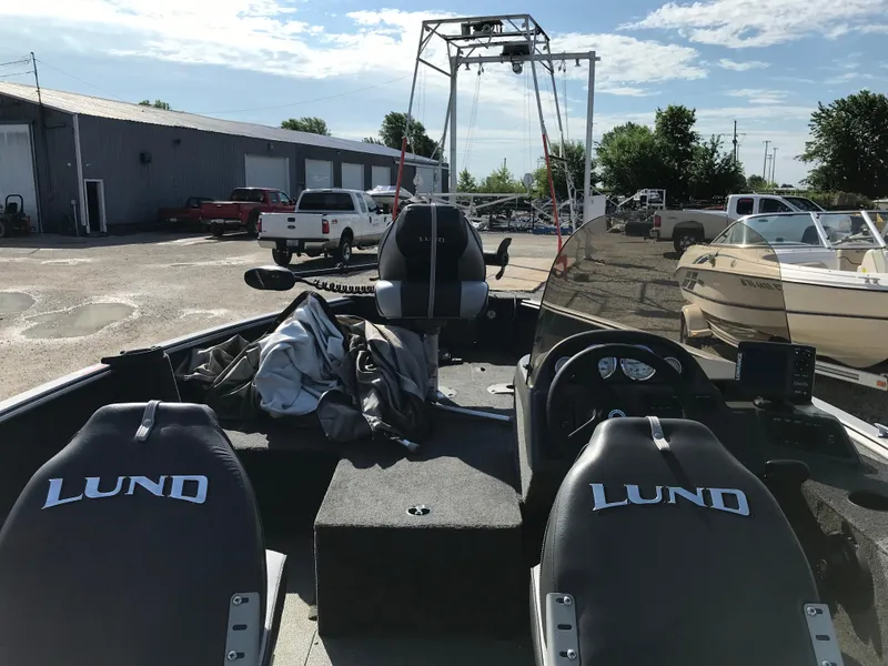 Slide: The Image of 2011 Lund 1775 Impact boat interior with seats and dashboard, parked outdoors. - 11