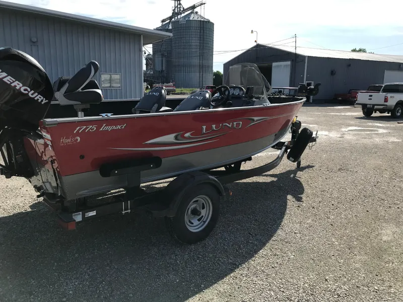 Slide: The Image of 2011 Lund 1775 Impact boat on trailer, parked outdoors near industrial buildings. - 3