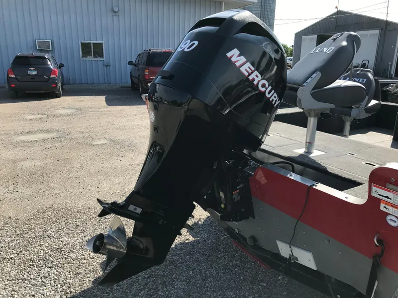 Slide: The Image of 2011 Lund 1775 Impact boat with Mercury outboard motor, parked on gravel near a building. - 8