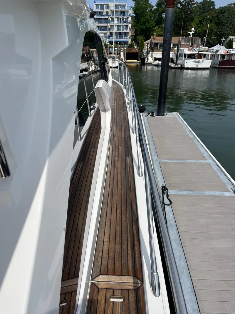 Slide: The Image of 2014 Azimut 55S yacht docked, showcasing sleek design and wooden deck. - 7