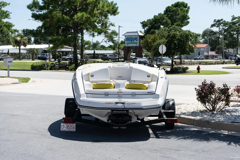 Slide: The Image of 2017 Scarab 165 G boat on trailer in parking lot, surrounded by trees and buildings. - 2