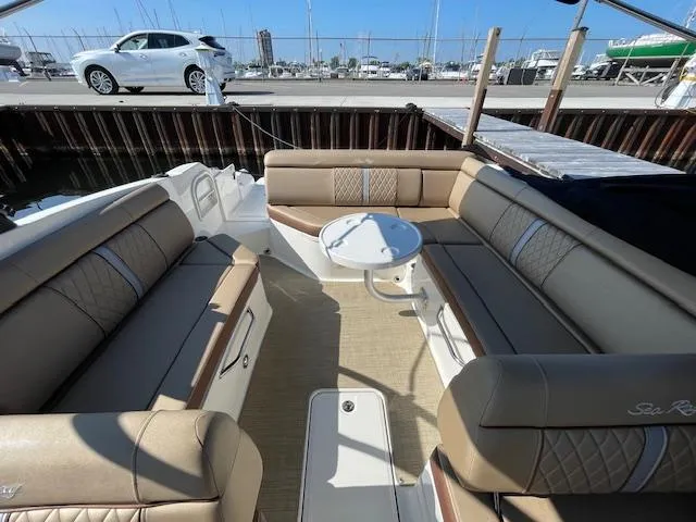 Slide: The Image of 2017 Sea Ray SDX 270 boat interior with beige seating and round table at marina. - 4
