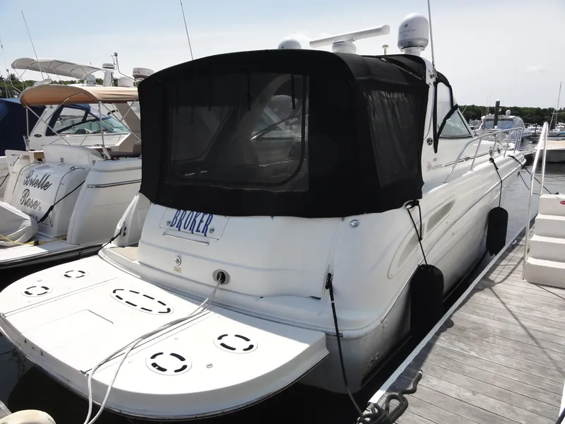 Slide: The Image of 2003 Sea Ray 380 Sundancer docked at marina, rear view with black canopy. - 2