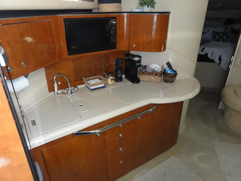 Slide: The Image of 2003 Sea Ray 380 Sundancer yacht kitchen with wood cabinets, sink, and microwave. - 22