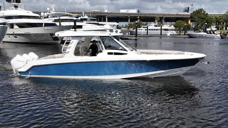 Slide: The Image of 2020 Boston Whaler 350 Realm boat cruising in a marina, featuring a sleek blue and white design. - 0